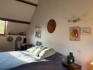 A bedroom with a bed, a desk, a chair, and wall-mounted artwork. - Country House on the Greenway (Colligis-Crandelain)
