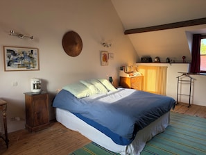 Ein Schlafzimmer mit einem Bett, einem Holzschrank, einer Heizung und einem Fenster mit Vorhängen.