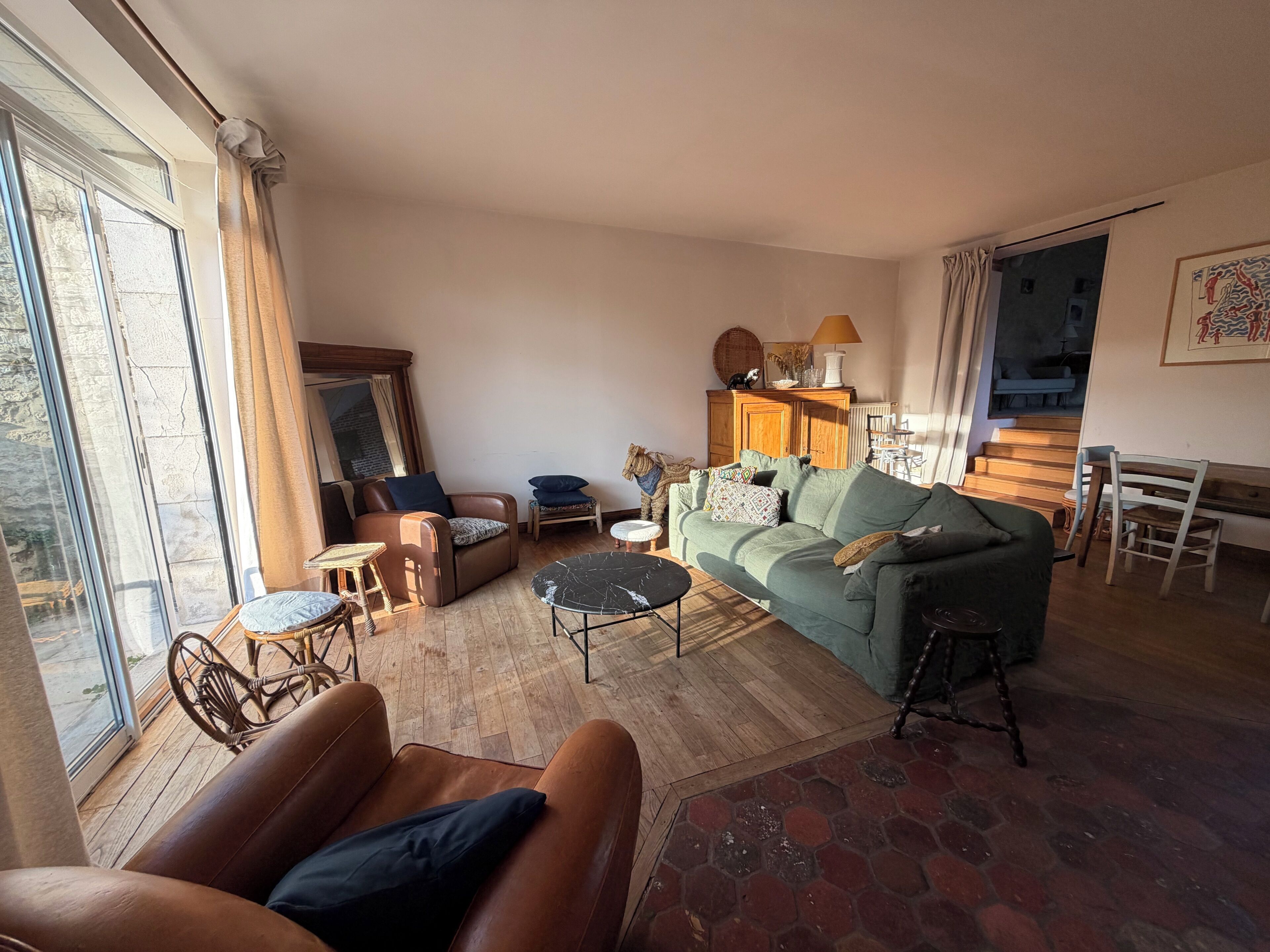 A spacious living room with a sofa, armchair, and a dining table.