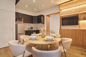 A modern kitchen with dark cabinets, a built-in microwave, and a large flat-screen TV. - Superb apartment center of Paris (Paris)
