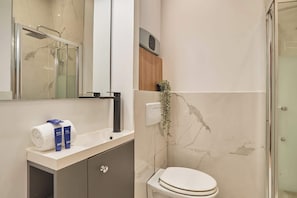 A bathroom with a toilet, a sink with toiletries, a mirror, and a shower area. - Superb apartment center of Paris (Paris)