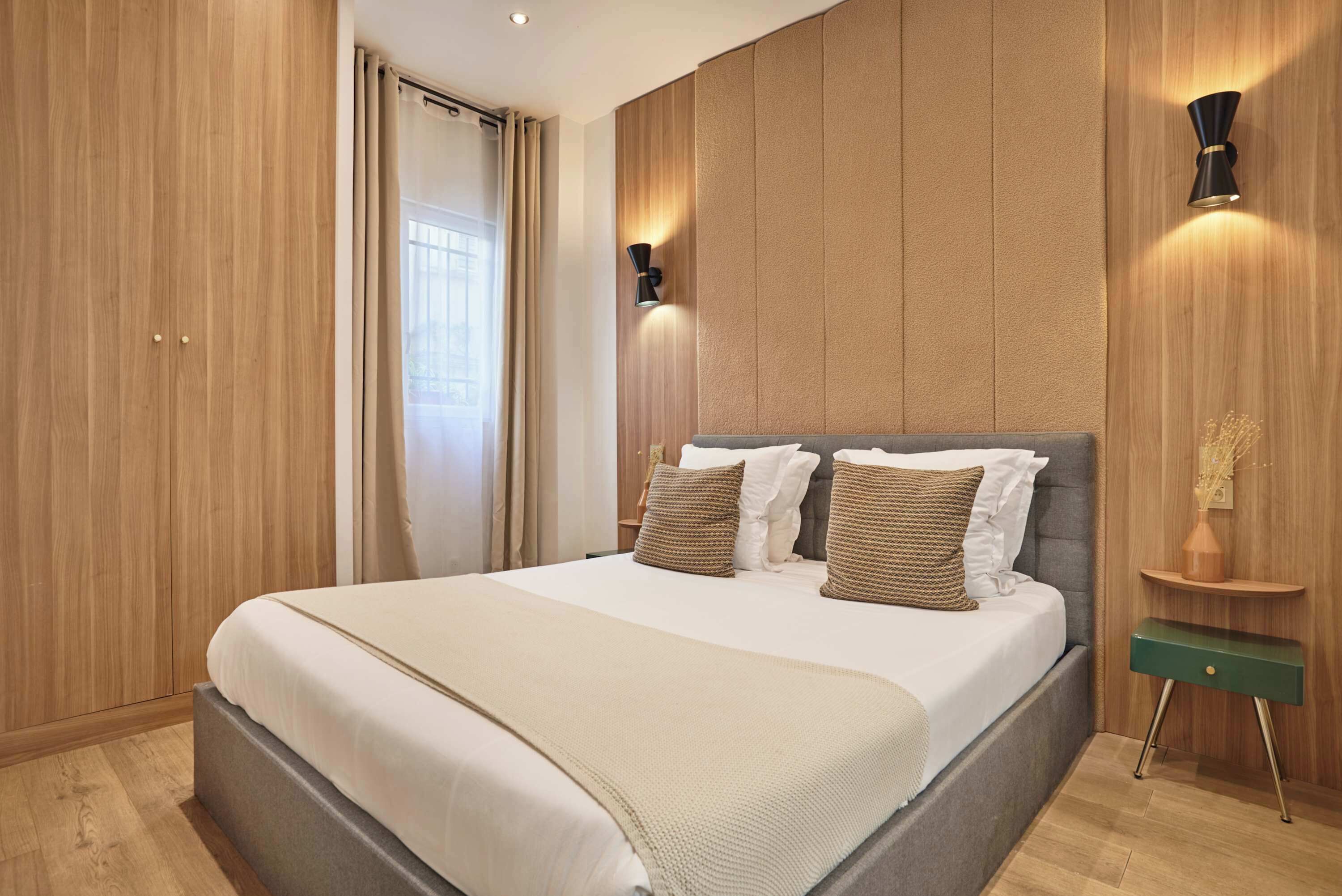Un dormitorio moderno con una cama grande, paneles de madera y dos luces fijadas a la pared.