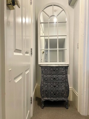 A hallway with a white door, a white-framed mirror, and a black and white patterned cabinet. - SEA LA VIE is a cosy apartment situated 10 minutes walk from the sea. (Unknown)