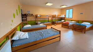 A dormitory room with bunk beds, a desk, and a chair.