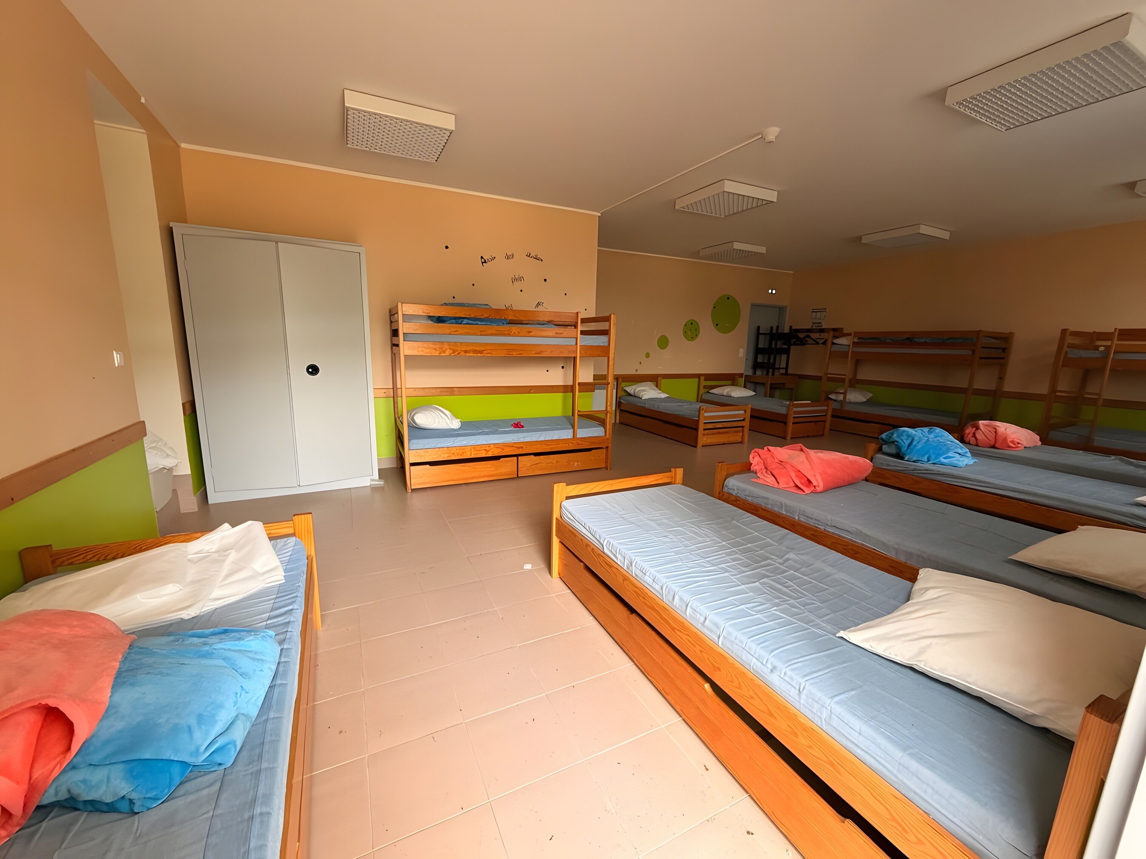 Une chambre de dortoir avec des lits superposés, une armoire et une porte.