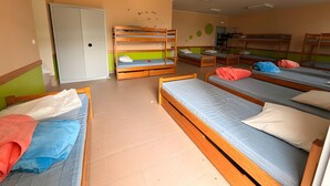 A dormitory room with bunk beds, a wardrobe, and a door.