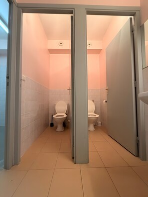 Une salle de bain avec deux toilettes, un lavabo et un miroir.