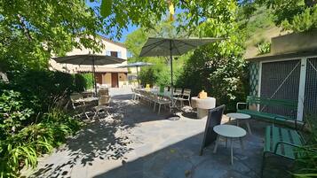 Un patio exterior con mesas, sillas, sombrillas y plantas.