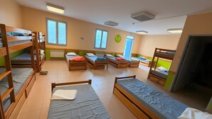 A dormitory room with bunk beds, a window, and a door.