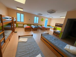 Une chambre de dortoir avec des lits superposés, une fenêtre et une porte.