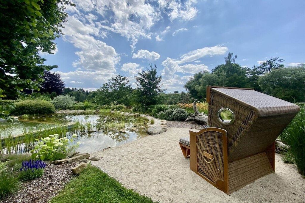 Ein Garten mit Teich, einem Stuhl und einem Holzbauwerk.
