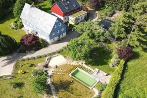 A residential property with a swimming pool, a red-roofed building, and a large house with a blue roof. - "To the forest disc" (Rammenau)