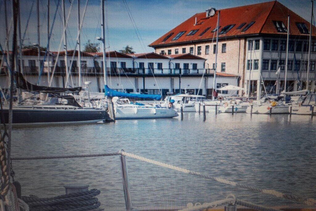 A marina with boats docked, a building with a red roof, and a clear sky.
