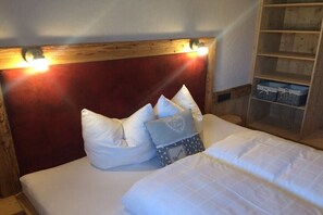A bed with white bedding, a red headboard, and a nightstand with a lamp.