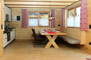 A wooden interior with a dining table, benches, and a kitchen area. - Holiday cabins Lechtal Chalet (Elbigenalp)
