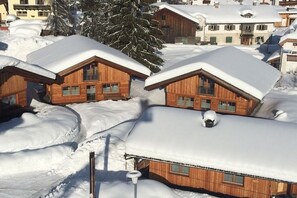 A cluster of wooden cabins with snow-covered roofs, surrounded by snow.