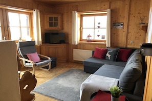 Un salon confortable avec un canapé, un fauteuil et un téléviseur.