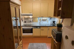 A compact kitchen with wooden cabinets, a stainless steel sink, and a microwave. - Alpine Bliss-Hochkrimml (Krimml)