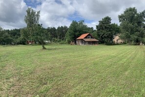 Un paysage rural avec une grange et une maison, entourés d’arbres et de champs ouverts.