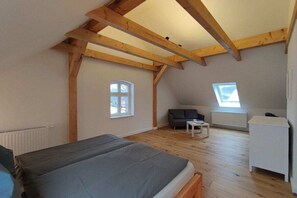A room with a bed, a sofa, a small table, and a radiator. - Zartwitzer Hütte Forest Lodge (Rechnlin)
