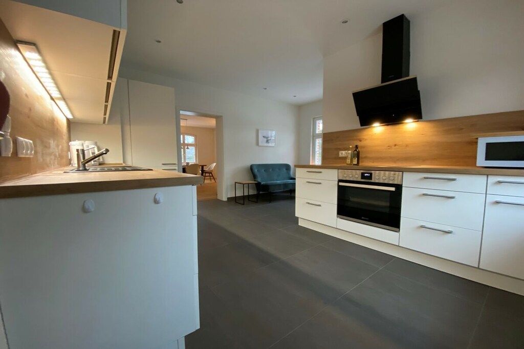 Een moderne keuken met witte kastjes, een inbouwoven en een magnetron.