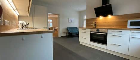 Een moderne keuken met witte kastjes, een inbouwoven en een magnetron.