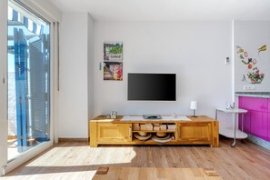 A modern bathroom with a wooden vanity, a flat-screen TV mounted on the wall, and a window with a view of the city. - Calahonda Beach III – Beachfront Apartment with Sea Views in Mijas Costa (Mijas Costa)