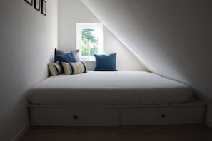A small, sloped ceiling room with a bed, pillows, and a window. - Holiday home with 3 bedrooms (Döhnsdorf)