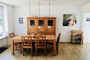 A dining area with a wooden table and chairs, a cabinet with glass doors, pendant lights, and a painting on the wall. - Holiday home with 3 bedrooms (Döhnsdorf)