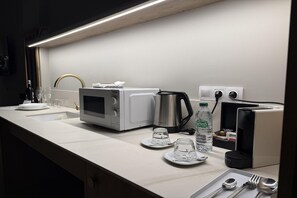 A kitchenette with a microwave, coffee maker, and a bottle of water. - Apartment La Plaza 2 double standard (Alicante)