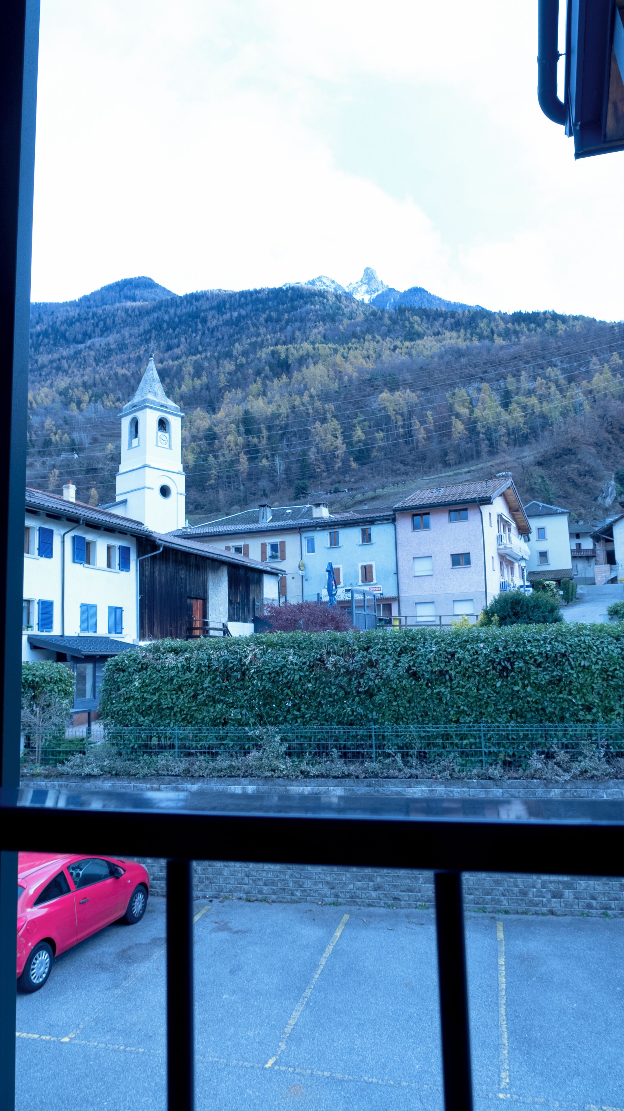 Une vue d’une ville avec un clocher d’église, des bâtiments et une montagne en arrière-plan.