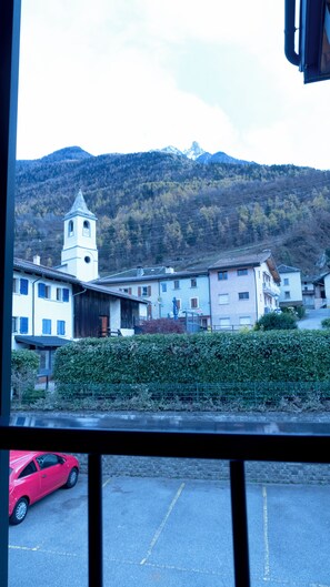 Une vue d’une ville avec un clocher d’église, des bâtiments et une montagne en arrière-plan.