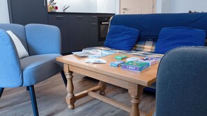 Une pièce avec une table en bois, deux chaises bleues et un lit avec une literie bleue.