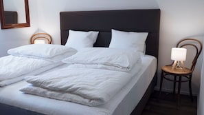 A neatly made bed with white linens and pillows, a dark headboard, and a bedside table with a lamp. - Brilliant apartment in Saxon for your getaway (Saxon)