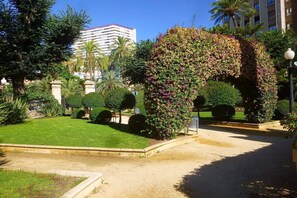 A landscaped garden with a central arch covered in flowers, surrounded by well-maintained grass and trees. - Apartment La Plaza 2 Deluxe with Jacuzzi (Alicante)