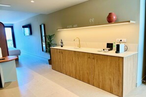 Una cocina moderna con una isla de madera, un lavamanos empotrado y una encimera con diversos objetos.