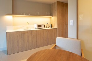Eine moderne Küche mit Holzausstattung, einer Mikrowelle und einer Kaffeemaschine.