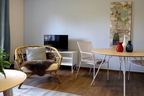 A living room with a television, wicker chairs, a round table, and decorative vases. - Holiday apartment with 1 bedroom (Malchow)