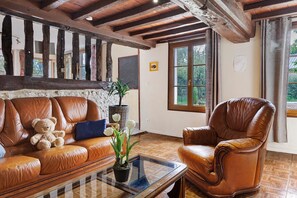 Une pièce comprenant un canapé en cuir marron, un fauteuil en cuir marron, une table basse en verre et une plante en pot.