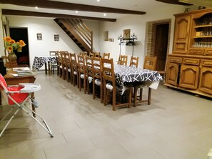 A dining area with a long table, chairs, and a staircase.