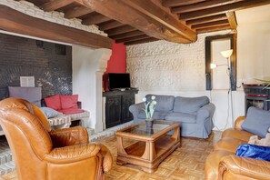 A living room with leather chairs, a sofa, a glass coffee table, and a television.