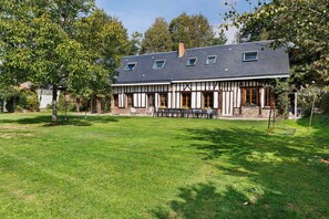 A two-story house with a sloped roof, a front porch with a bench, and a well-maintained lawn.