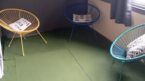 Ein Zimmer mit drei Stühlen, einer mit einem Kissen mit Vogelmotiven, ein anderer mit einem Kissen mit Vogelmotiven und ein dritter mit einem gemusterten Kissen.