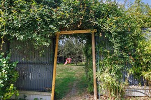 A wooden arbor with a pathway leading to a playground.