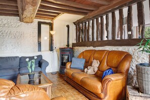 A cozy living room with a leather sofa, a blue armchair, and a glass coffee table.