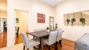 Uma sala de jantar com uma mesa retangular, seis cadeiras e piso de azulejos.