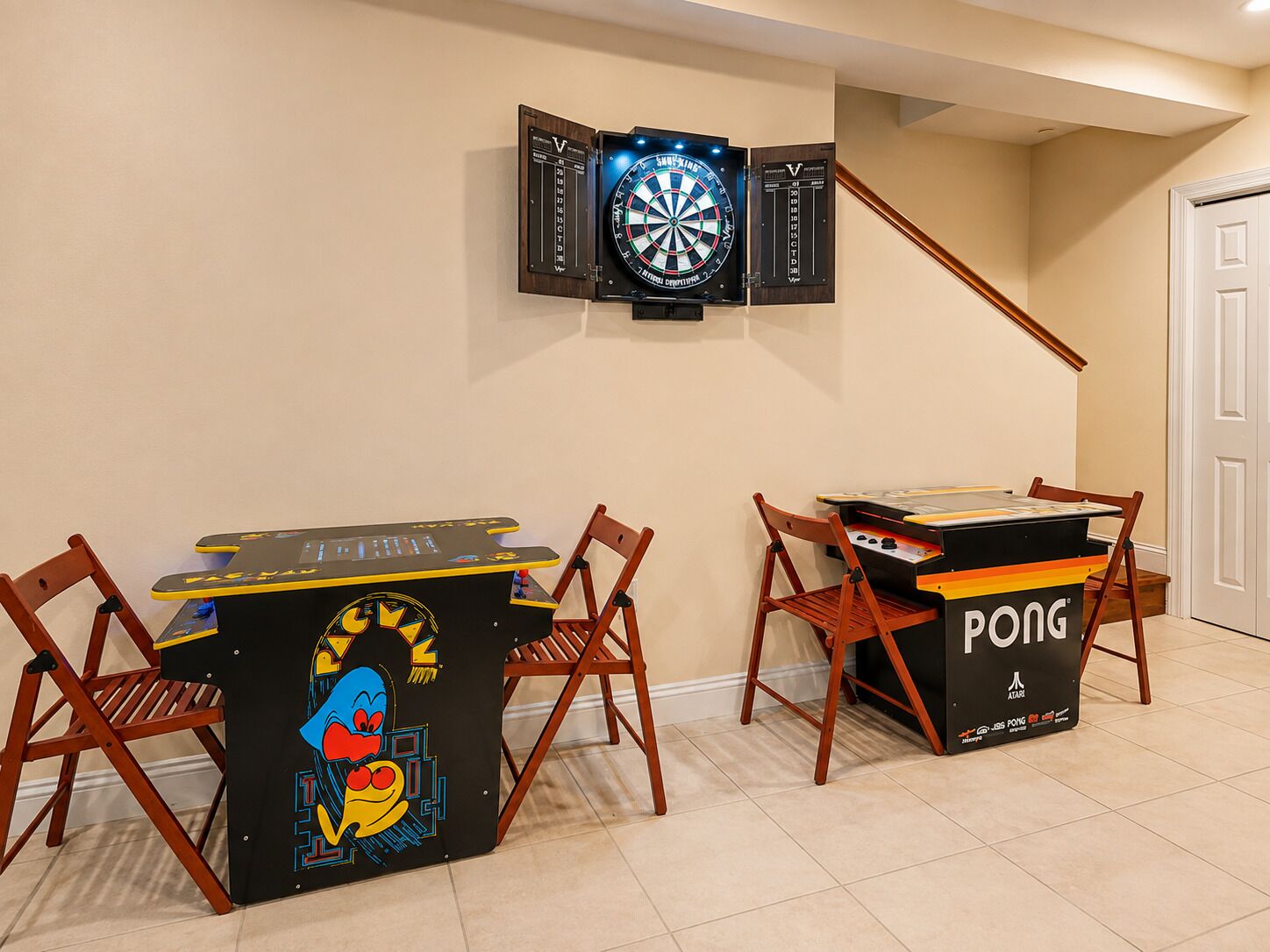 A room with a dartboard mounted on the wall, a ping pong table, and two wooden chairs.