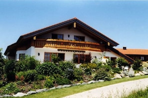 A two-story house with a sloped roof, a balcony, and a well-maintained garden. - Holiday apartment with 1 bedroom (Missen-Wilhams)