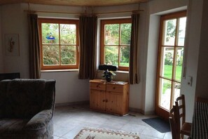 Una habitación con sofá, un armario de madera y una ventana con cortinas.