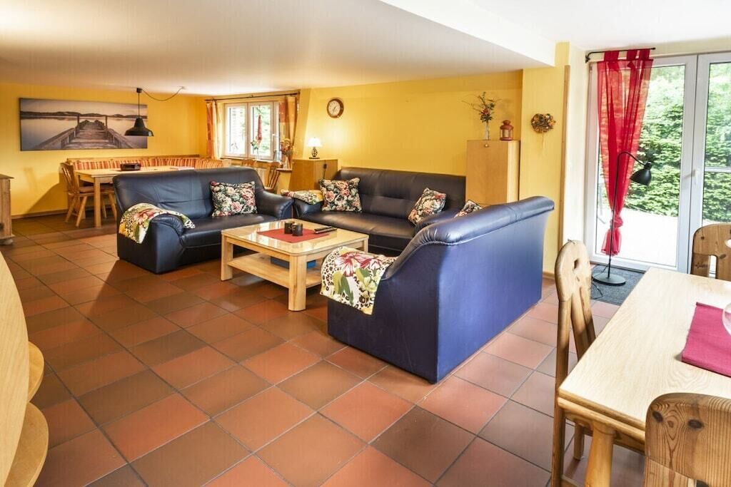 A living room with a sofa set, a coffee table, and a dining area with a table and chairs.